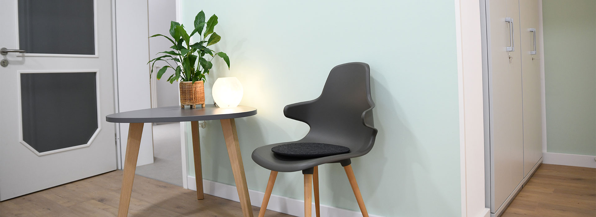 Wartebereich mit Stuhl, Tisch, Lampe und Blume